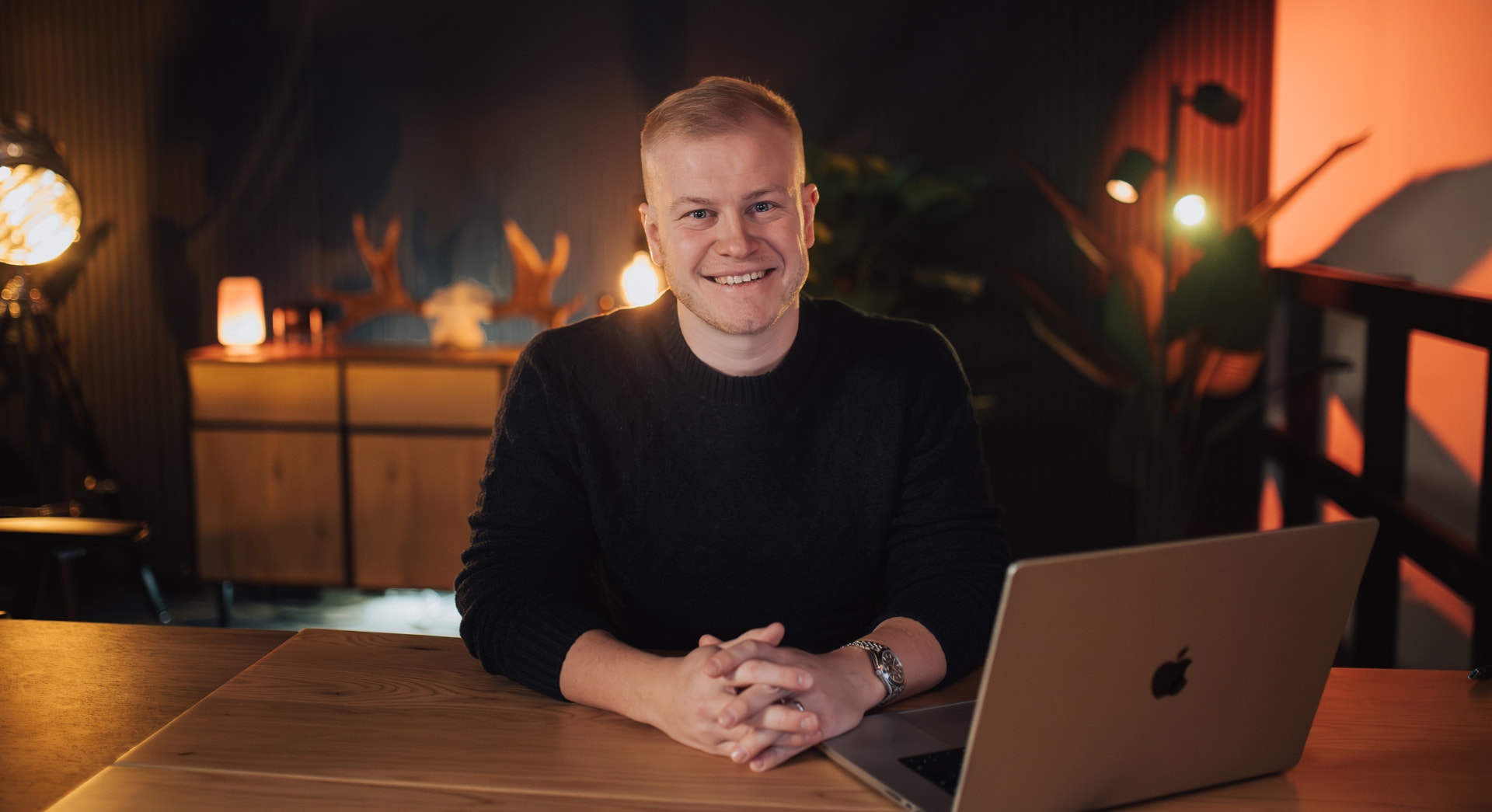 The founder at a lamp-lit desk in a dark Nordic studio